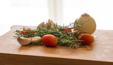 close-ups of tomatoes, rosemary and garlic on wooden board