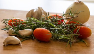 close-ups of tomatoes, rosemary and garlic on wooden board