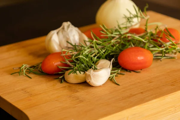close-ups of tomatoes, rosemary and garlic on wooden board