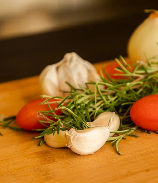 close-ups of tomatoes, rosemary and garlic on wooden board