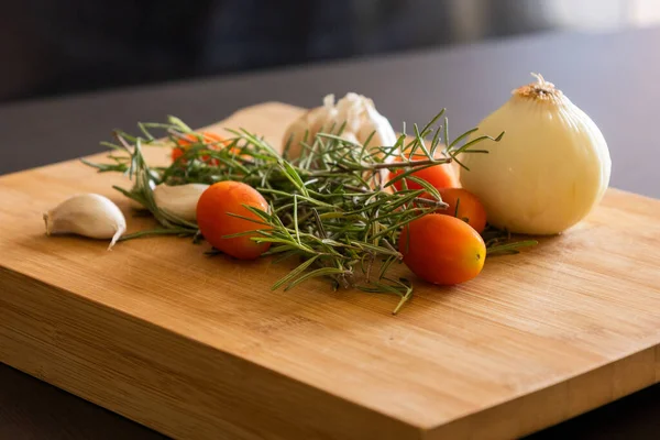 close-ups of tomatoes, rosemary and garlic on wooden board