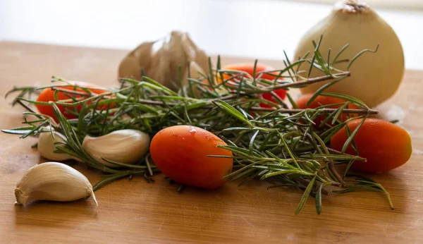 close-ups of tomatoes, rosemary and garlic on wooden board
