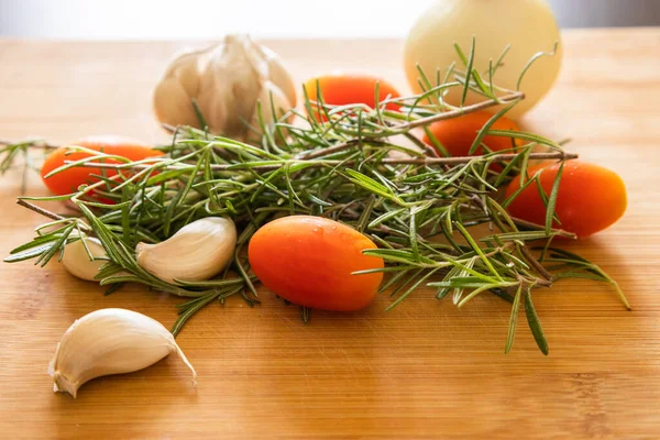 close-ups of tomatoes, rosemary and garlic on wooden board