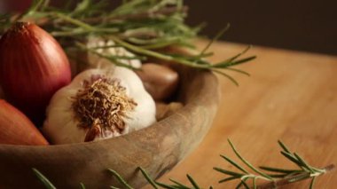 fresh raw onions, garlic, rosemary close up in wooden bowl