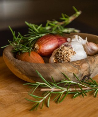 fresh raw onions, garlic, rosemary close up in wooden bowl