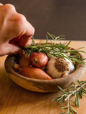fresh raw onions, garlic, rosemary close up in wooden bowl