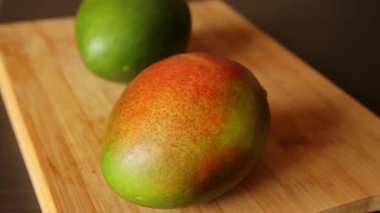 two mangos close up on wooden board