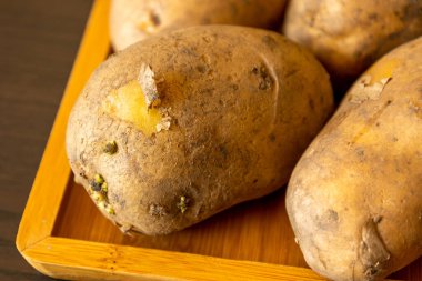 close up raw potatoes on wooden table at home