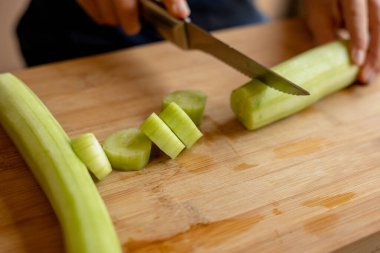 cutting cucumber at home on wooden board close up