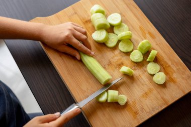 cutting cucumber at home on wooden board close up