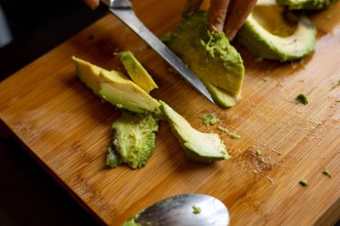 cutting avocado on wooden board close up at home