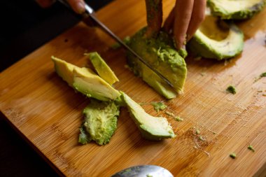 cutting avocado on wooden board close up at home