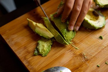 cutting avocado on wooden board close up at home