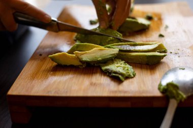 cutting avocado on wooden board close up at home