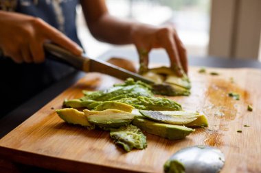 cutting avocado on wooden board close up at home