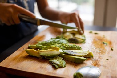 cutting avocado on wooden board close up at home