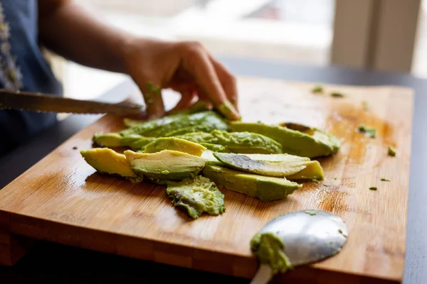 cutting avocado on wooden board close up at home