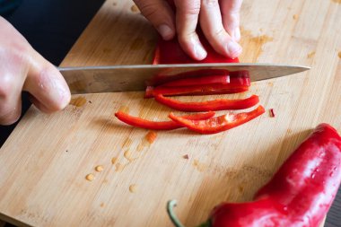 Erkek elleri kırmızı biberi tahta tahtaya yakın kesiyor.