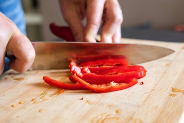 Erkek elleri kırmızı biberi tahta tahtaya yakın kesiyor.