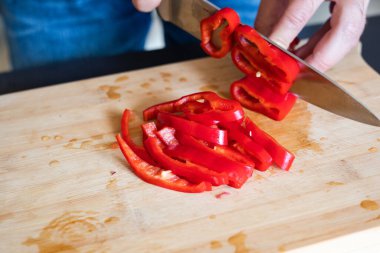 Erkek elleri kırmızı biberi tahta tahtaya yakın kesiyor.