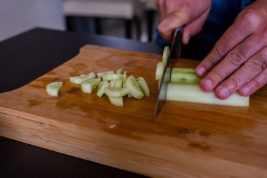 Erkek elleri taze salatalıkları kesiyor.