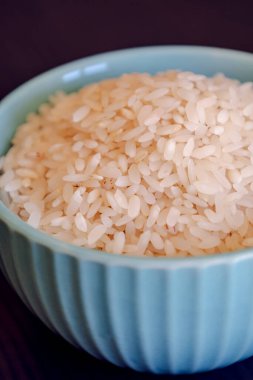 Küçük mavi kase, çiğ beyaz pirinç ile kaplan.