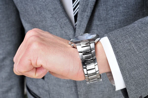 Um homem usando um terno olhando para seu relógio — Fotografia de Stock