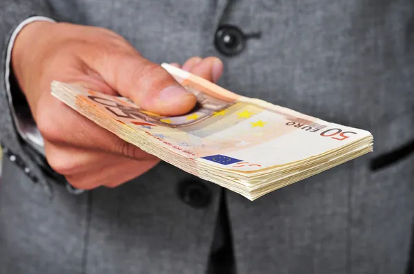Uomo in giacca e cravatta con un mazzo di banconote in euro — Foto Stock