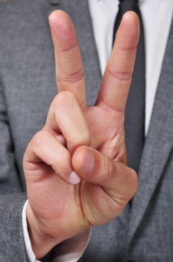 v işareti veren takım elbiseli adam
