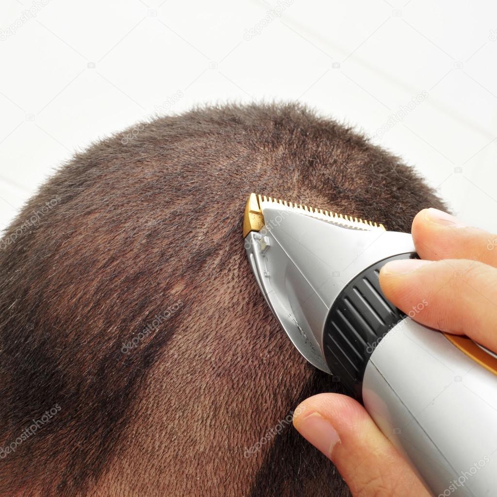 man cutting his hair with an electric hair clipper