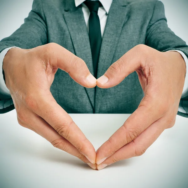 Hombre de traje formando un corazón con sus manos — Foto de Stock