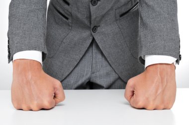 man in suit withs his fists on the desk clipart