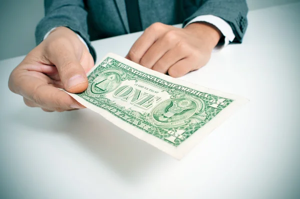 Hombre de traje ofreciendo un billete de un dólar estadounidense — Foto de Stock