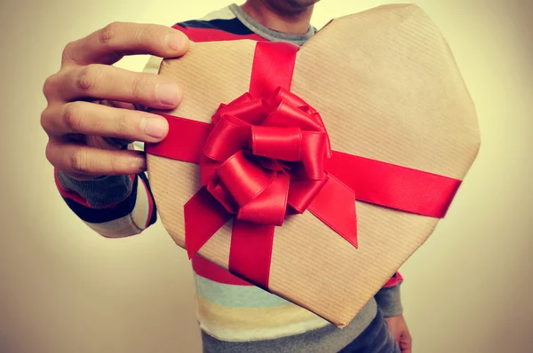 Young man with a heart-shaped gift — Stock Photo, Image