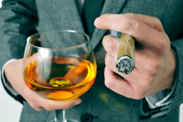 Homme en costume avec un cigare et un verre avec du brandy — Photo