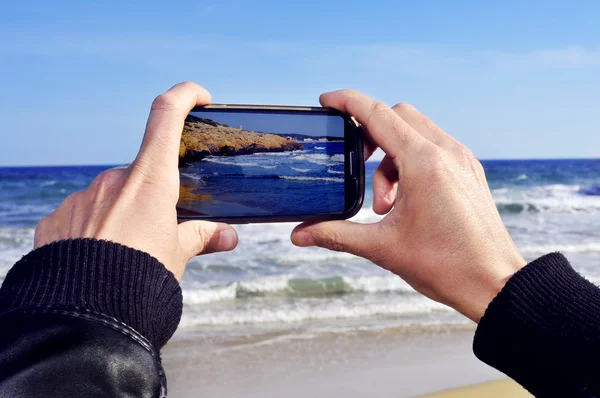 Alguien tomando una foto de una playa con un smartphone —  Fotos de Stock