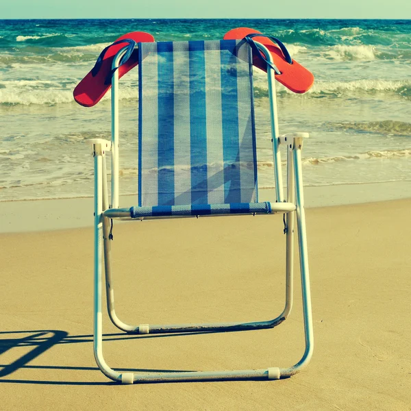 Leżak i pomarańczowe japonki na plaży, retro niebez — Zdjęcie stockowe