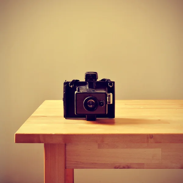 Vieja cámara instantánea sobre una mesa, con un efecto retro —  Fotos de Stock