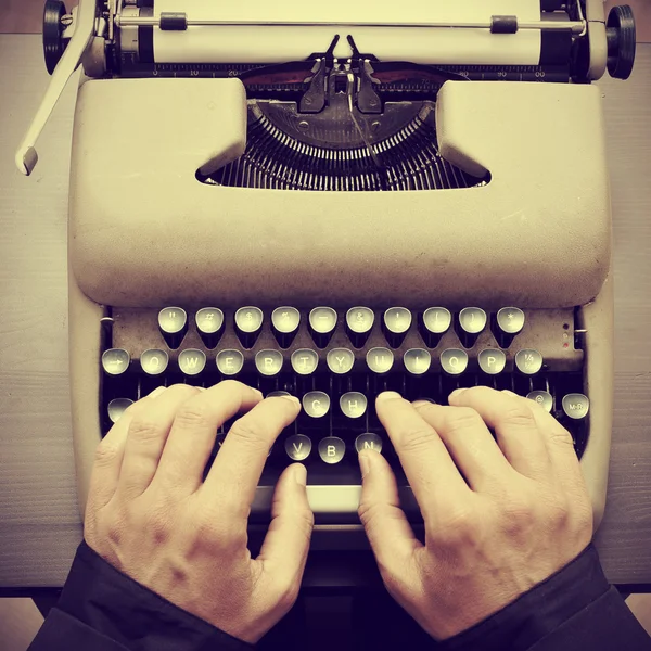 Man typing on an old typewriter, with a retro effect — Stock Photo, Image