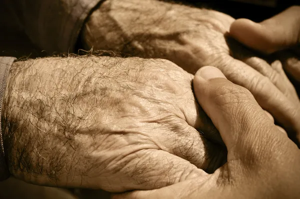 Joven sosteniendo las manos de un anciano — Foto de Stock