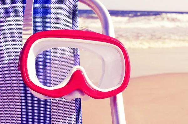 Diving mask hanging in a deckchair with a retro filter effect — Stock Photo, Image