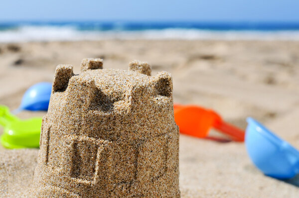 sandcastle and toy shovels on the sand of a beach