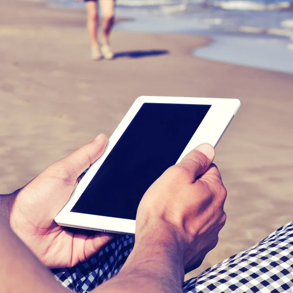 Adam bir retro doğurur ile sahilde bir tablet veya bir e-kitap kullanma — Stok fotoğraf