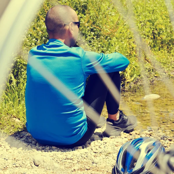Велосипедист отдыхает на берегу реки с ретро-фильтром e — стоковое фото