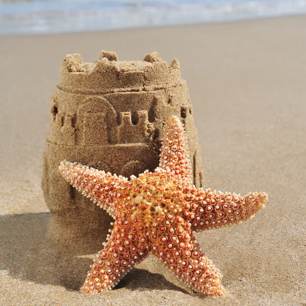 Estrella de mar y castillo de arena en la playa — Foto de Stock