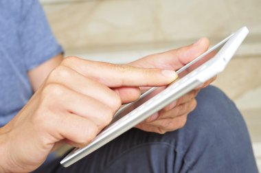 Genç adam tablet bilgisayar kullanıyor.