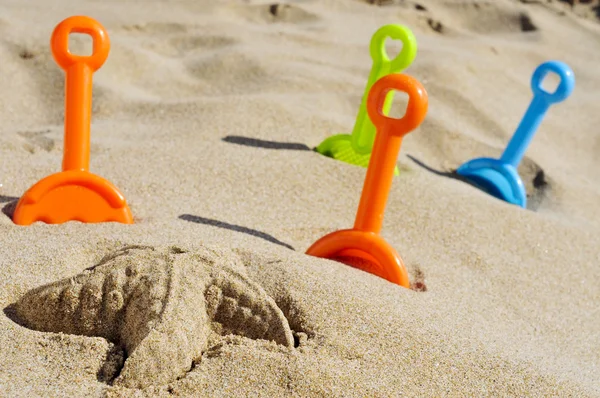 Estrellas de mar arena y palas de juguete de diferentes colores en la arena —  Fotos de Stock