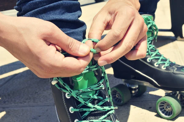 Joven atando sus patines, con efecto filtro — Foto de Stock