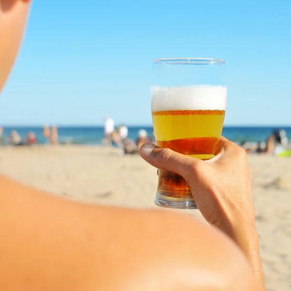 Giovane che beve una birra rinfrescante sulla spiaggia — Foto Stock