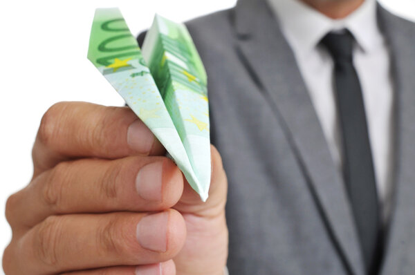 Бизнесмен с бумажным самолетом, сделанным с банкнотой в 100 евро
